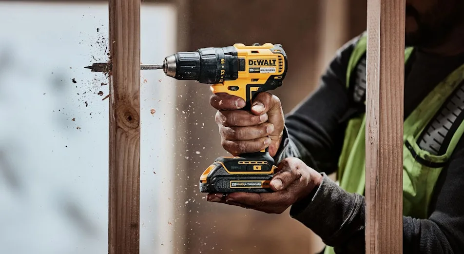 Gula DeWalt-batteriskruvdragare som borrar i en trästolpe med flisor som sprutar.